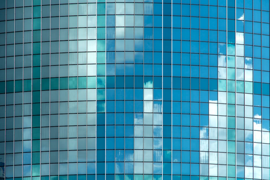Facility Management Company Reflective glass windows of a modern building displaying cloud patterns