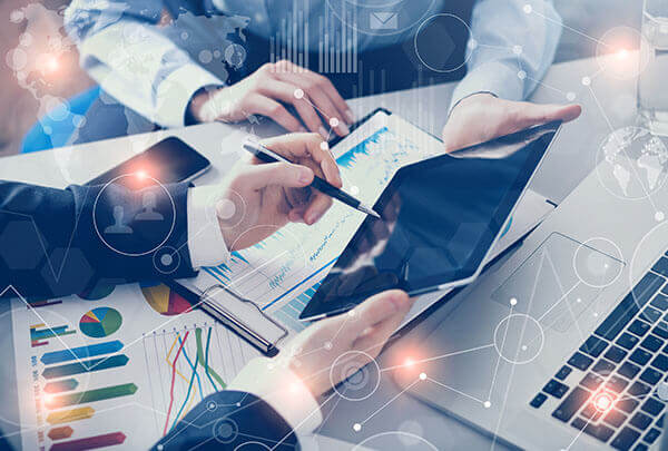 Facility Management Company Business professionals reviewing financial charts and data on a tablet and laptop.