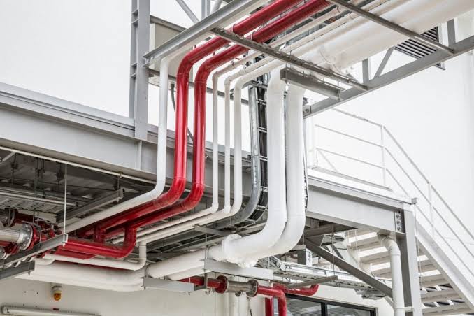 Facility Management Company Industrial piping system with red and white pipes, part of hard services.